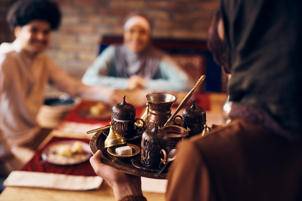 Close-up of traditional Muslim woman serving Turkish coffee on at home.