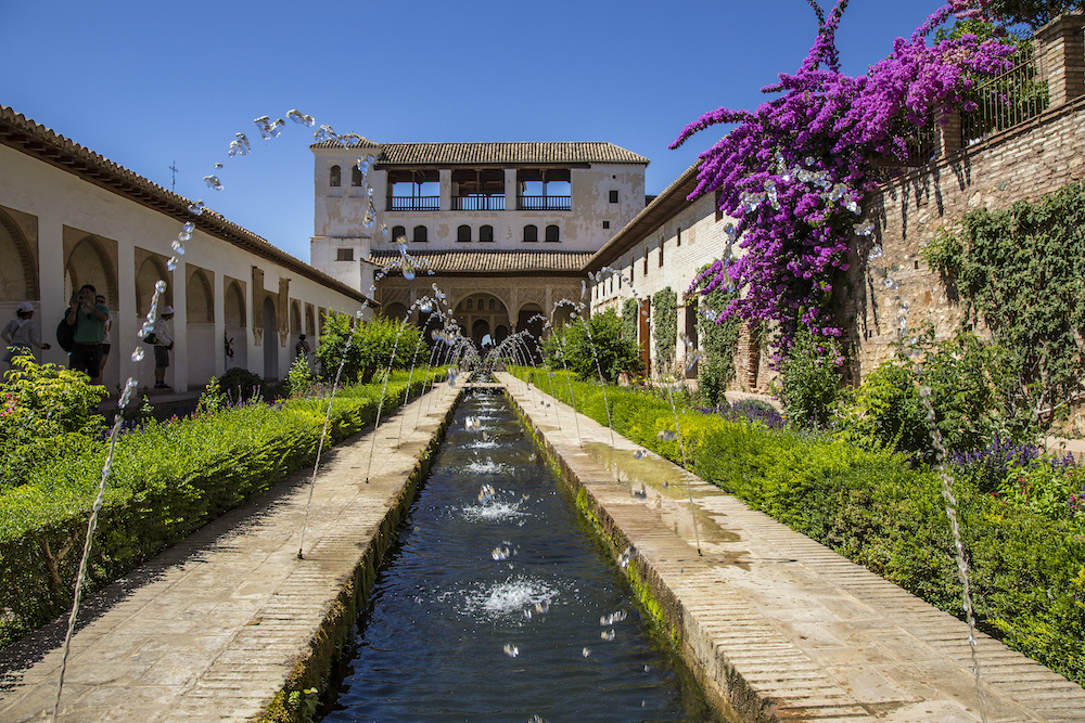 Granada, Andalucia / Spain »; July 2018: Water jets in the gardens of Generalife Alhambra with the building in the background